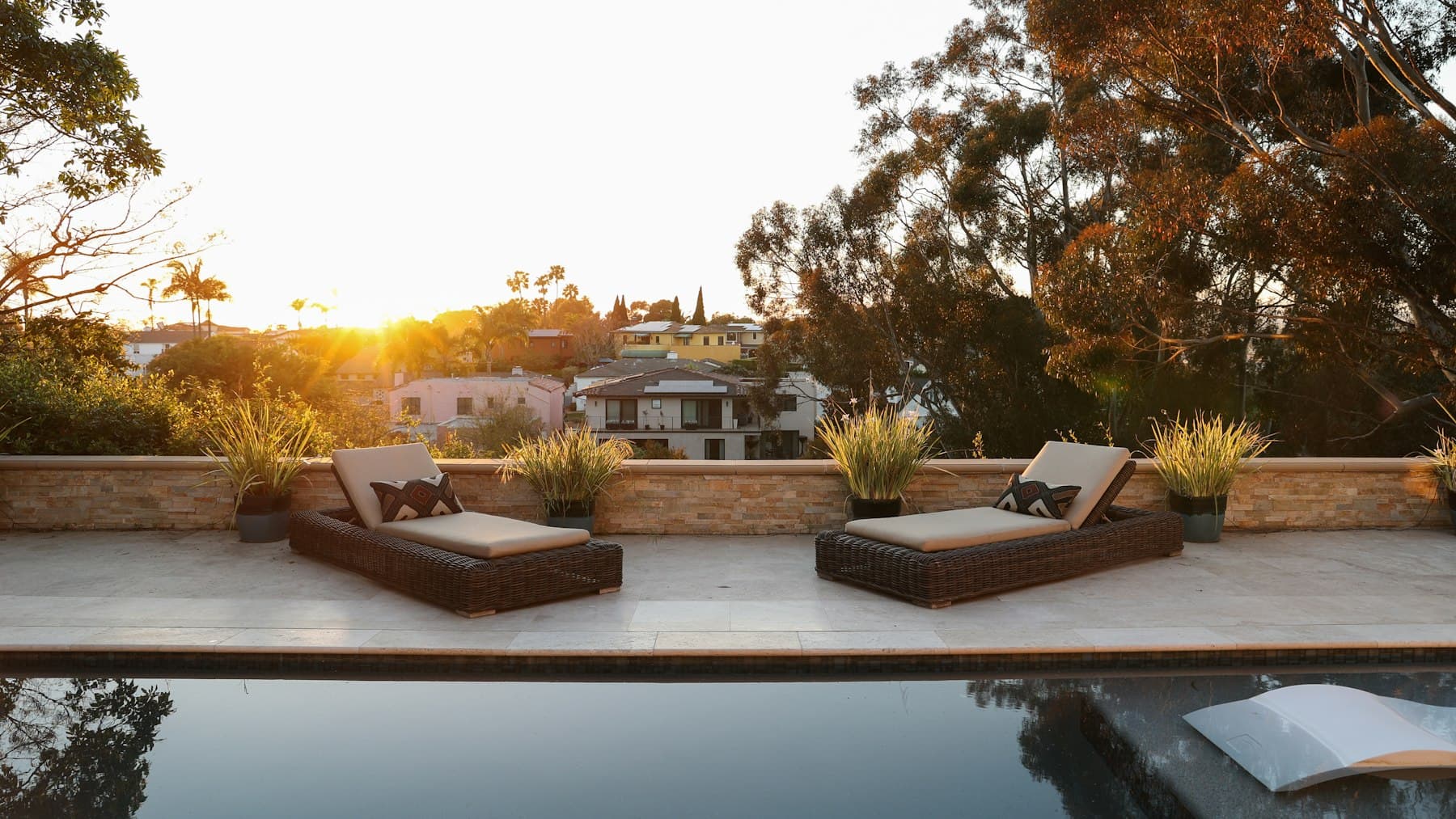 Backyard swimming pool with lounge chairs beside a home, illustrating fiberglass versus concrete pool choices