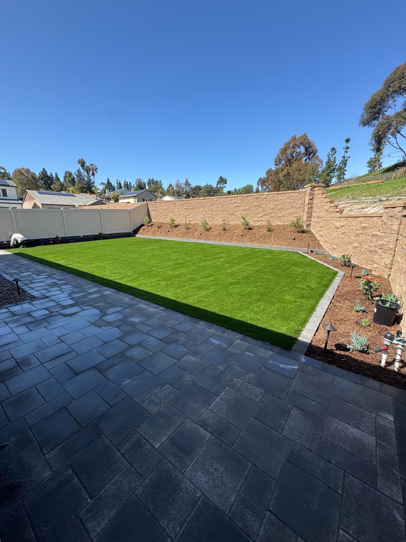 Charcoal paver patio with an artificial turf lawn and retaining wall, installed by Modern Yardz in San Diego