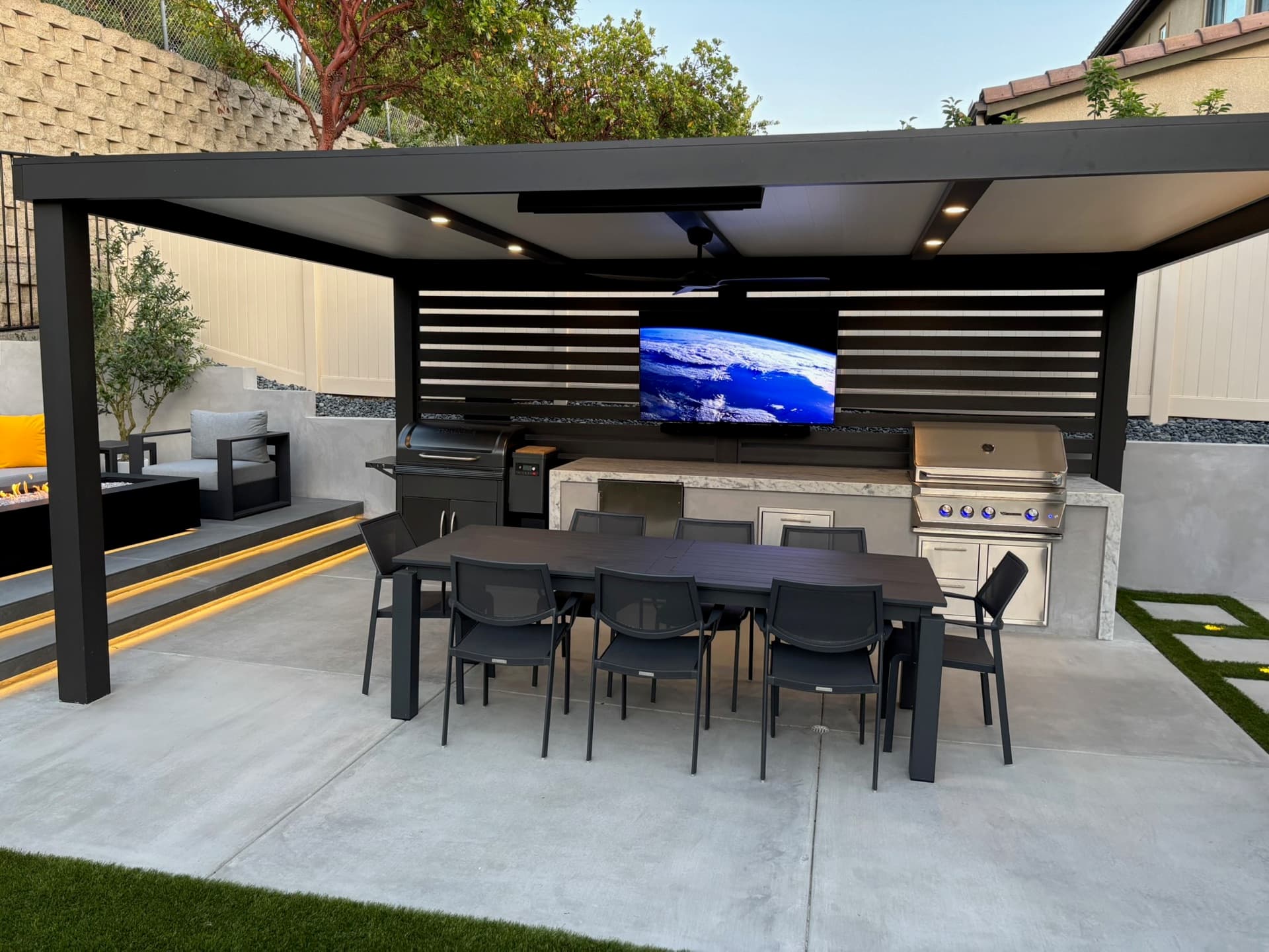 Louvered pergola, outdoor kitchen, and fire lounge at dusk, designed and built by Modern Yardz in Carmel Valley, San Diego County
