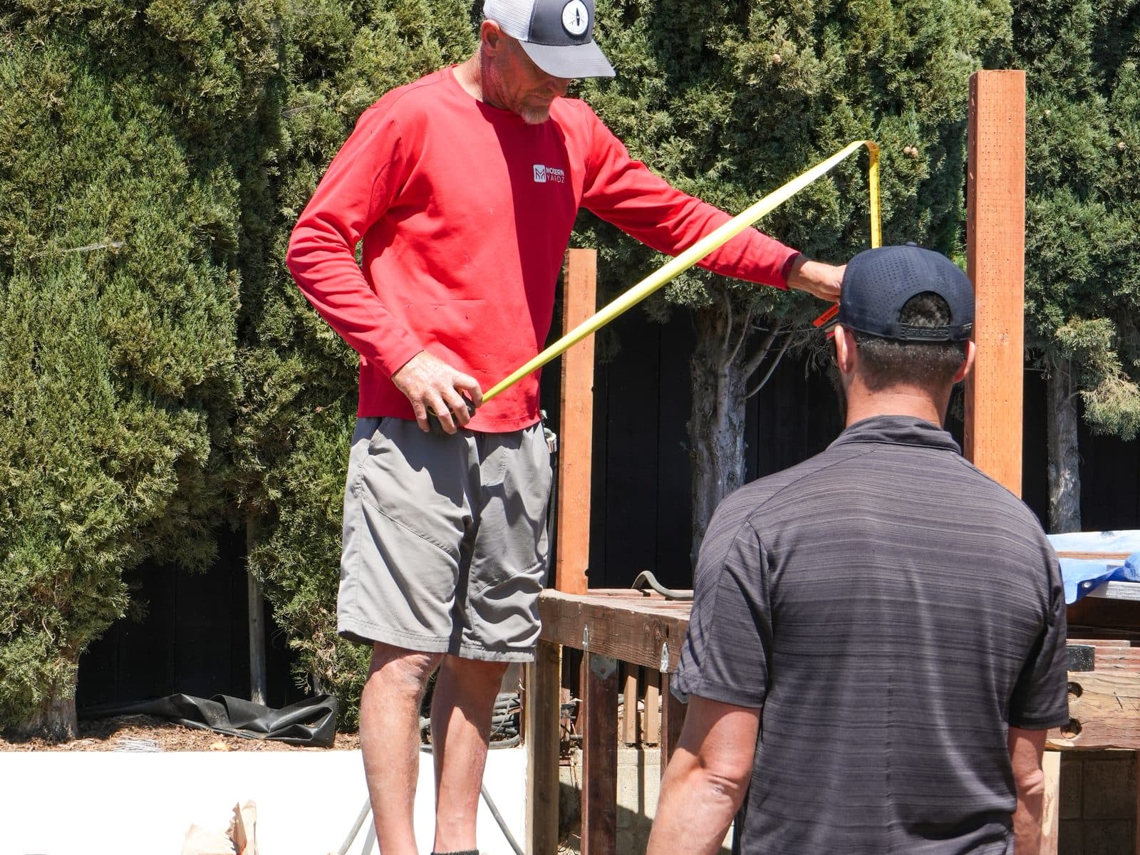 Modern Yardz carpenter measuring a pergola beam before installation in San Diego